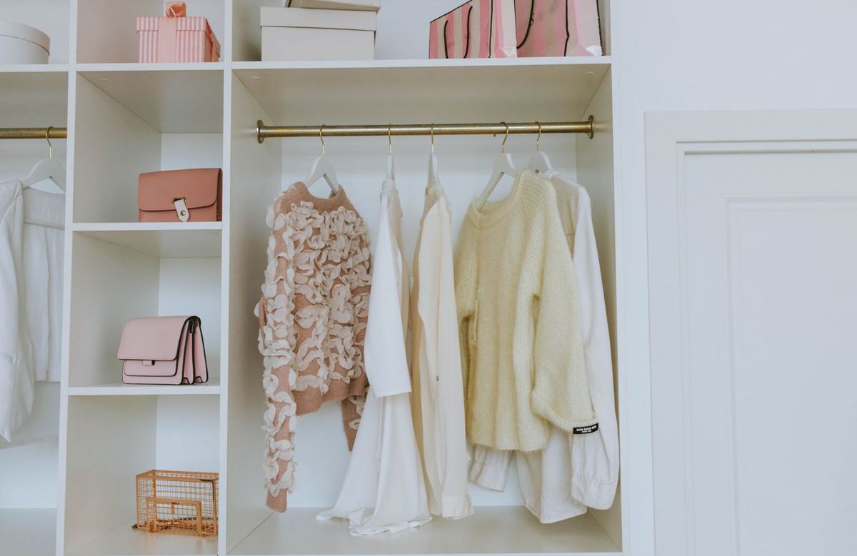 An organized closet with clothes and bags on open shelving